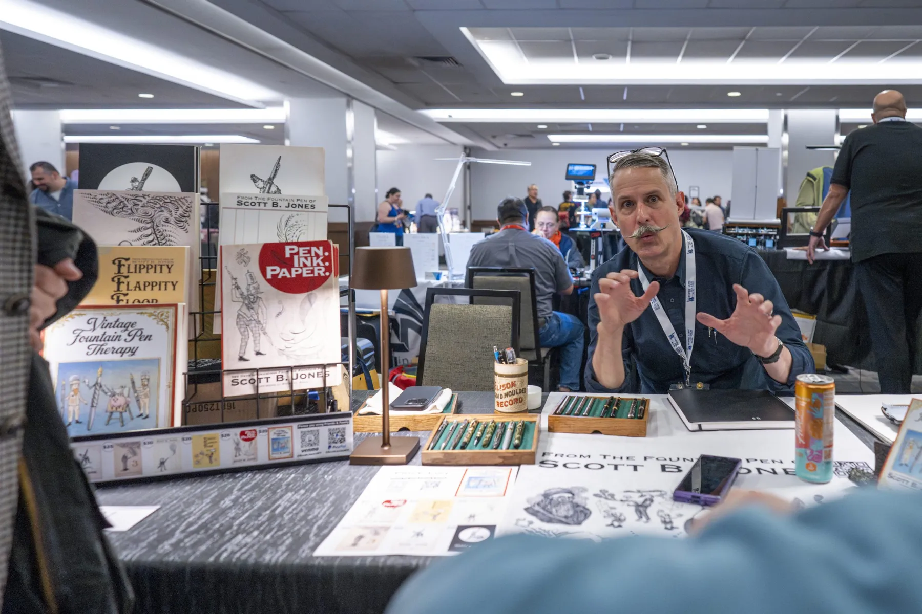 An exhibitor sharing pens and artwork at the Empire State Pen Show
